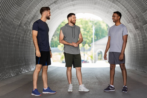 young sporty men or male friends talking outdoors - Фото, изображение