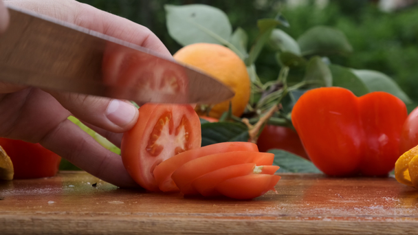 Ręczne cięcie pomidorów z nożem na drewnianej płycie. - Materiał filmowy, wideo