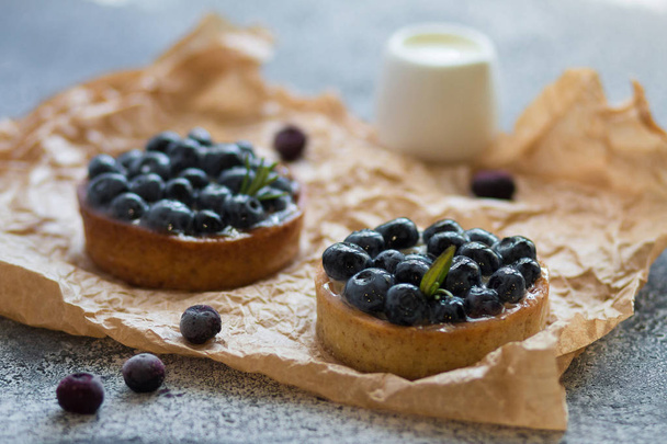 Delicious blueberry tartlets with vanilla custard cream on gray background. Front view.  - Photo, Image