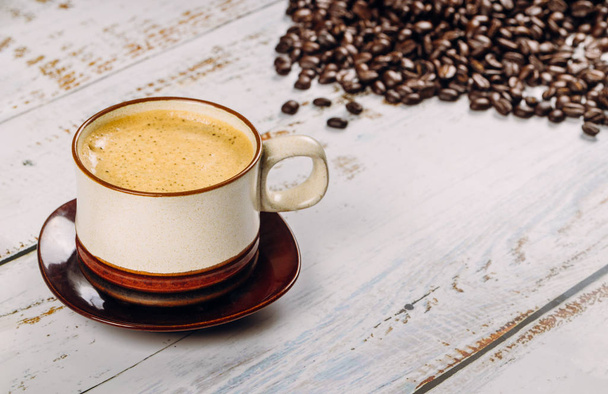 Чорна чашка кави та квасоля на дерев'яному фоні столу
 - Фото, зображення