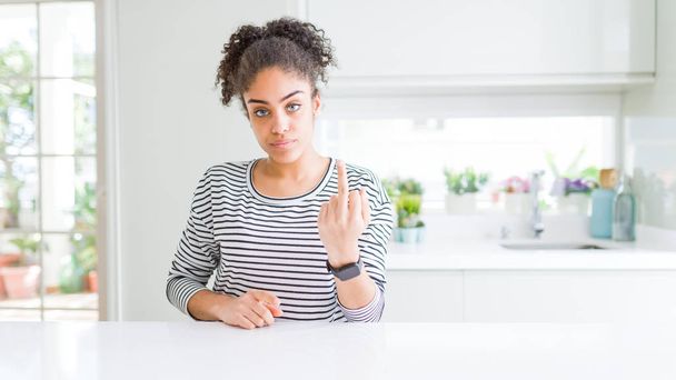 Gyönyörű afro hajú afro-amerikai nő alkalmi csíkos pulóvert visel Középső ujj, udvariatlan és durva fasz off kifejezés mutatása - Fotó, kép