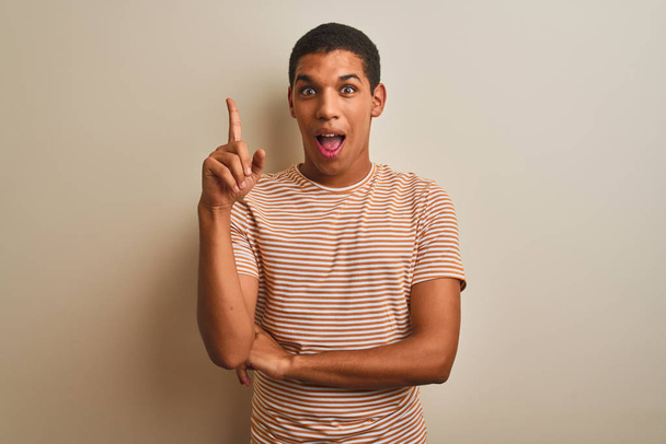 Young handsome arab man wearing striped t-shirt over isolated white background pointing finger up with successful idea. Exited and happy. Number one. - Foto, Imagem