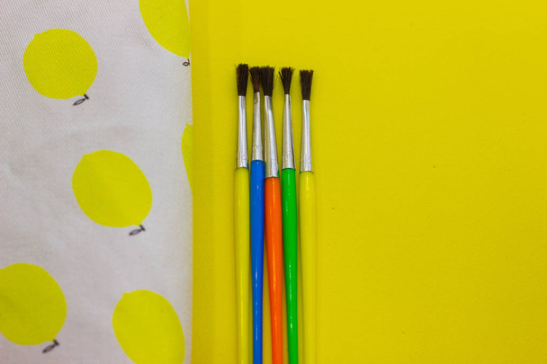 Cepillos y estuche de lápices sobre fondo amarillo. De vuelta a la escuela. Vista en la parte superior y espacio de copia
 - Foto, Imagen