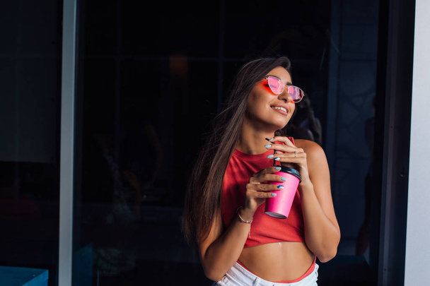 Stylish happy young brunette woman holding pink cup of coffee to go. - Fotoğraf, Görsel