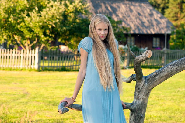Beautiful young girl with long blond hair in blue dress in the countryside - Foto, Imagem
