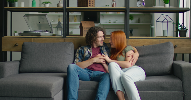 Young couple in love is relaxing on sofa at home, enjoying their relationships - Imágenes, Vídeo