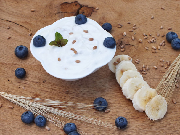 Yogurt with fruit on a board of oak in the garden - Photo, Image