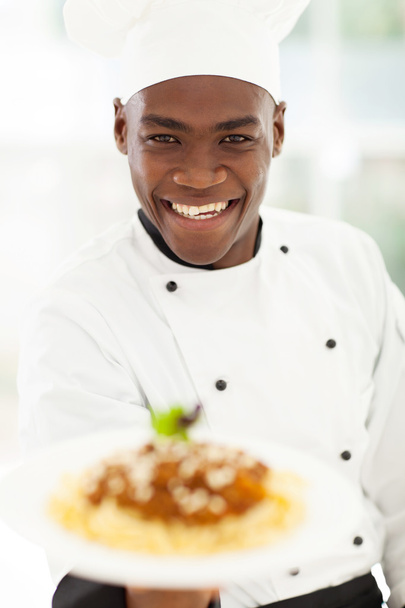 African chef in hotel kitchen presenting pasta - Фото, изображение