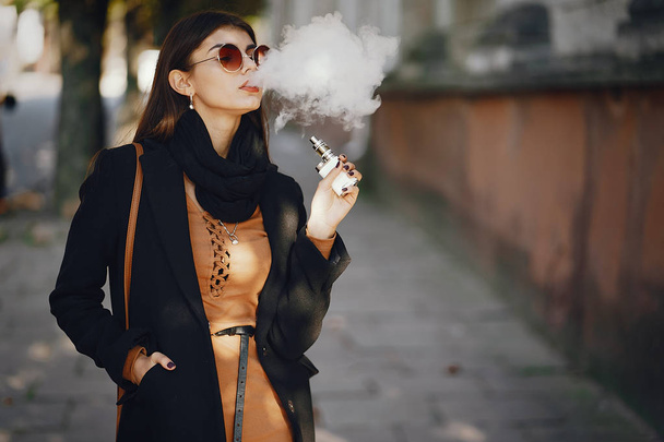Şık bir kız e-sigara içiyor. - Fotoğraf, Görsel