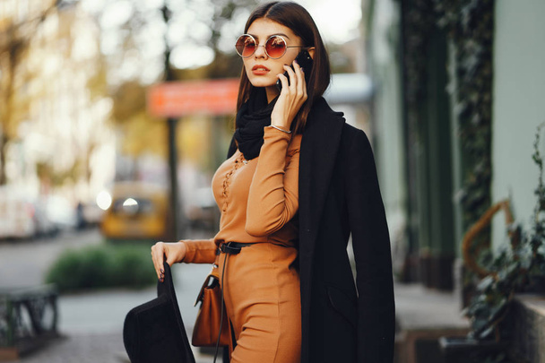 stylish girl walking through the city while using her phone - Foto, Bild