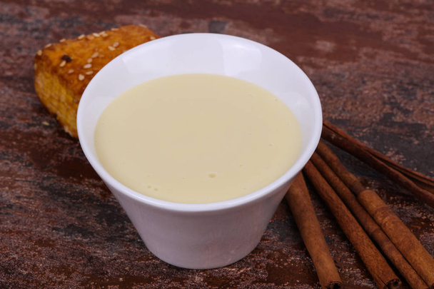 Condenced melk in de kom met sinnamon en gebak - Foto, afbeelding