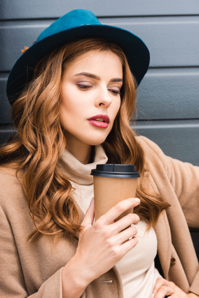 attractive woman in blue hat looking away and holding paper cup  - Photo, Image