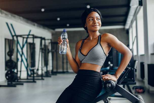 A beautiful black girl is engaged in a gym - 写真・画像