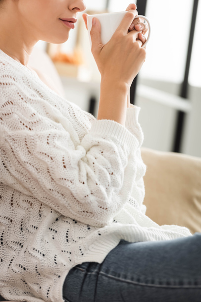 cropped view of woman in white sweater holding cup  - Photo, image