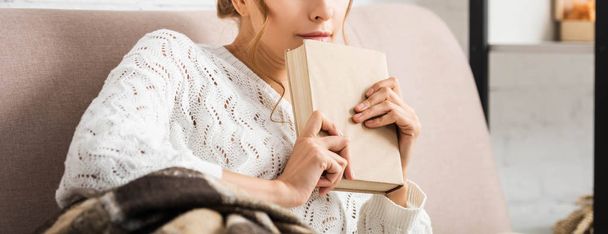 обрезанный вид женщины в белом свитере, держащей книгу
  - Фото, изображение