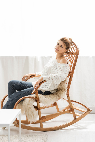 приваблива жінка в білому светрі сидить на кріслі
 - Фото, зображення