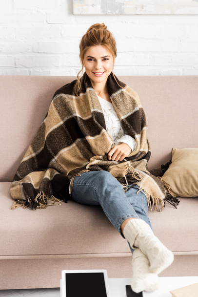 attractive woman with blanket sitting on sofa and looking at camera  - Φωτογραφία, εικόνα