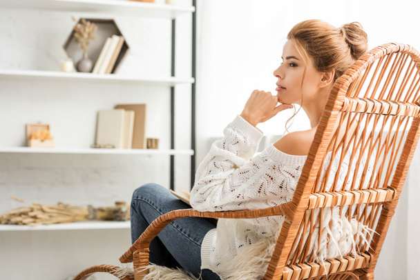 attraktive Frau im weißen Pullover sitzt auf Schaukelstuhl - Foto, Bild