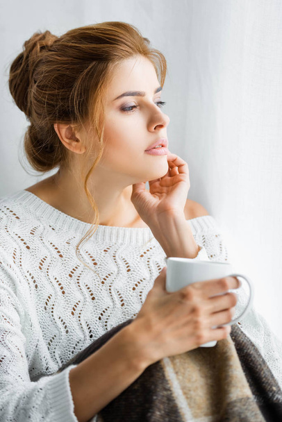attractive woman in white sweater with blanket holding cup  - Foto, Bild