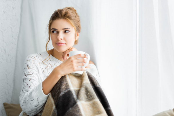 attractive woman in white sweater with blanket holding cup  - Valokuva, kuva