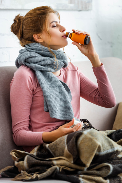 mujer atractiva y enferma con bufanda gris bebiendo jarabe para la tos
   - Foto, imagen