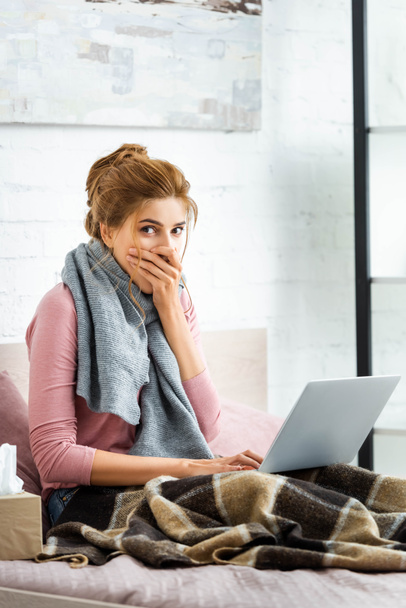 attractive and shocked woman with grey scarf holding laptop  - Foto, Bild