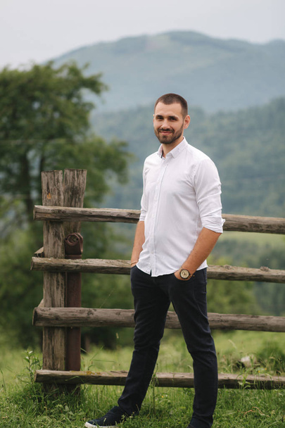 Handsome man in white shirt stand in front of Carpathian mountains and smile - Photo, Image