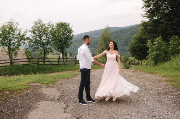 Mooie bruidspaar in de Karpaten. Knappe man met aantrekkelijke vrouw. Bruid spin rond - Foto, afbeelding