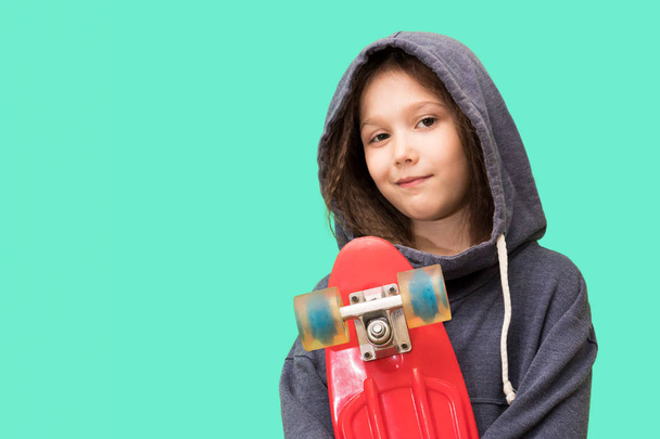 young girl with skateboard on a blue background - Foto, Bild
