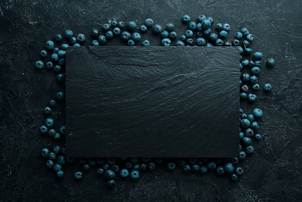 Fresh blueberries on a black stone background. Free copy space. - Fotoğraf, Görsel