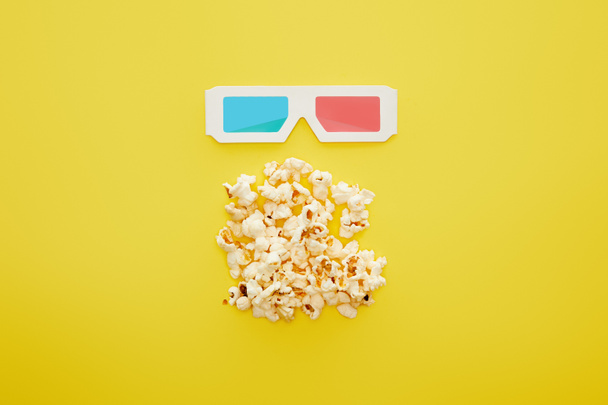 top view of delicious popcorn and 3d glasses on yellow background - Foto, Imagem