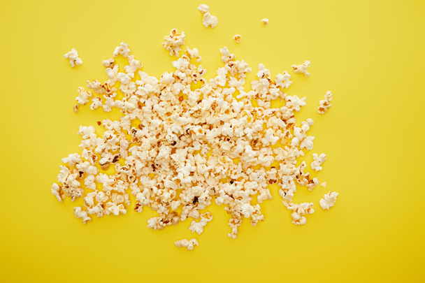 top view of tasty popcorn scattered on yellow background - Photo, Image