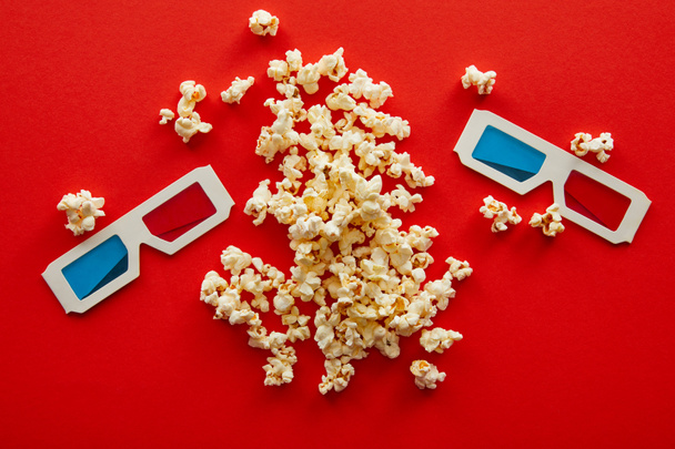 top view of delicious popcorn near 3d glasses on red background - Fotoğraf, Görsel