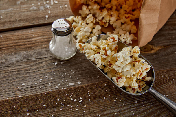 top view of delicious popcorn with salt scattered on wooden background - Foto, immagini