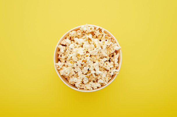 top view of delicious fresh popcorn in bucket on yellow background - Photo, Image