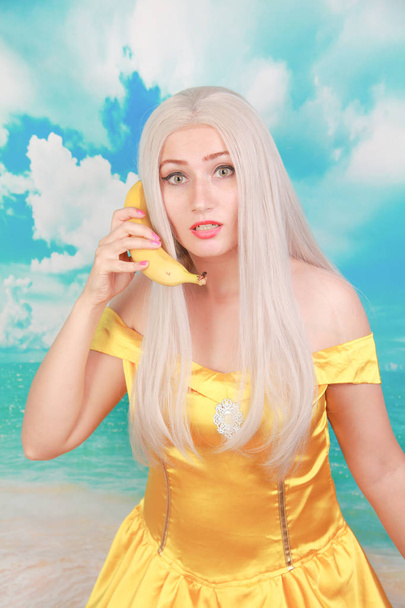 pretty girl in pinup yellow dress on blue background. banana dieting. - Photo, Image