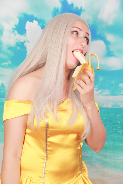 jolie fille en robe jaune pinup sur fond bleu. régime de banane
. - Photo, image