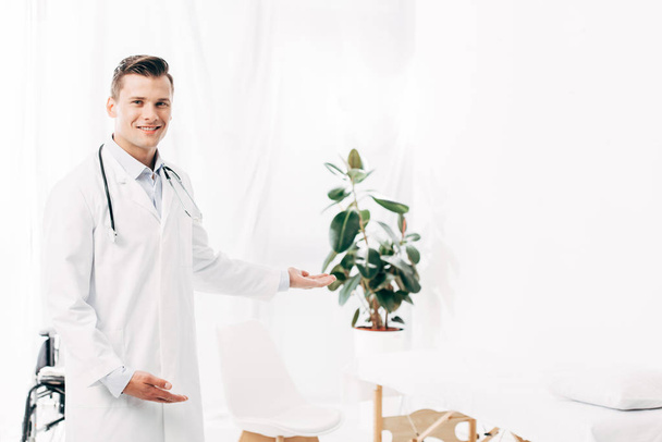 smiling doctor in white coat with stethoscope in clinic - Fotografie, Obrázek