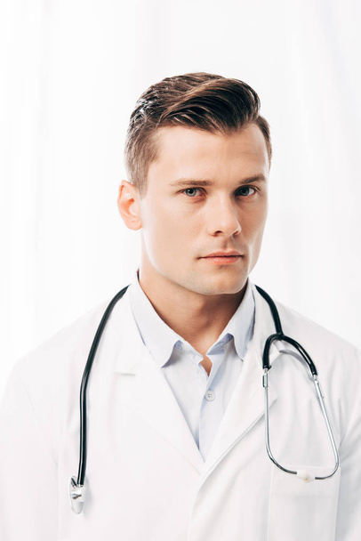 vakava lääkäri valkoisessa takissa stetoskoopilla katsomalla kameraa valkoisella
 - Valokuva, kuva