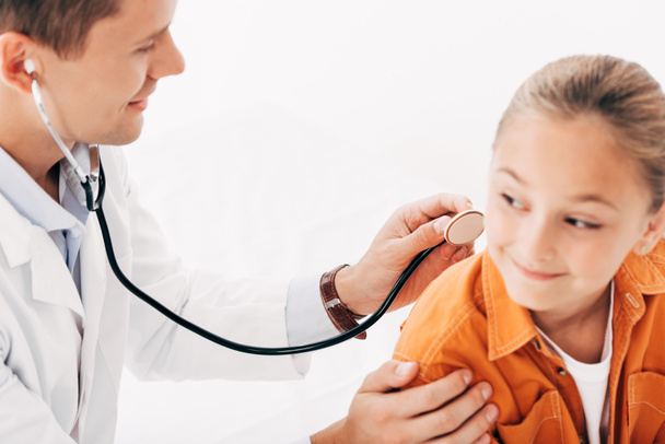 pediatrist in white coat examining kid with stethoscope isolated on white - 写真・画像