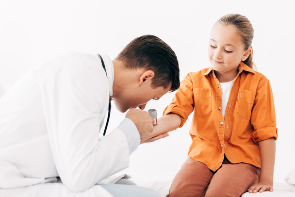 pediatrist w białej sierści badając dziecko z DermaScope - Zdjęcie, obraz