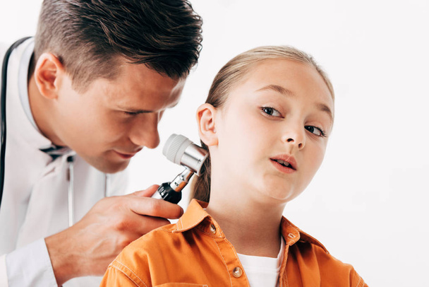 focused pediatrist in white coat examining child with dermascope isolated on white - Photo, image