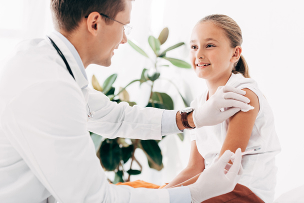 pediatra em luvas de látex fazendo injeção para criança
 - Foto, Imagem