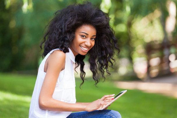 Outdoor portrait of a teenage black girl using a tactile tablet - Foto, imagen