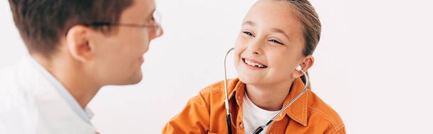 panoramic shot of smiling kid with stethoscope and pediatrist isolated on white - Zdjęcie, obraz