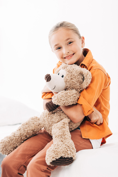 smiling child with teddy bear sitting on hospital bed - 写真・画像