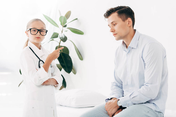 child in glasses and doctor costume examining patient - Foto, Imagem