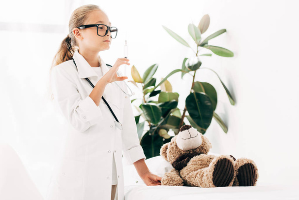 child in doctor costume and glasses holding syringe - Foto, immagini