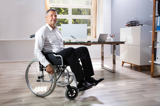 Handicapped Businessman Sitting On Wheelchair In Office - Foto, Imagem