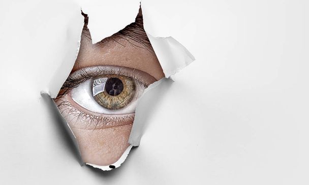 Eye in a hole of torn paper - Foto, imagen